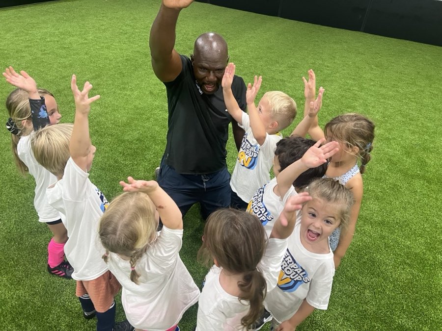 Soccer Pals players throwing their hands up with their coach