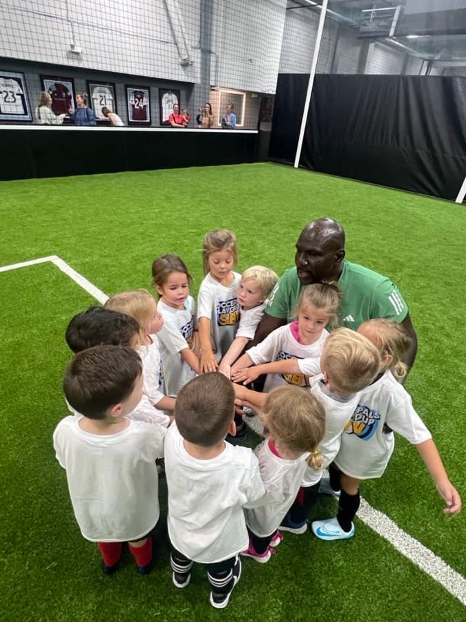Soccer Pals players in a huddle with their coach